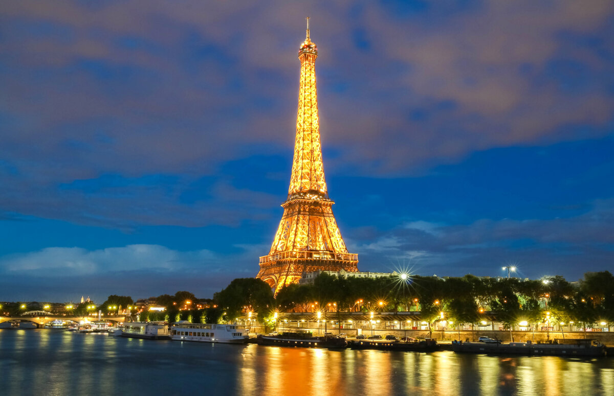 The Eiffel Tower illuminated at night, showcasing its iconic structure against a dusky sky in Paris, France.