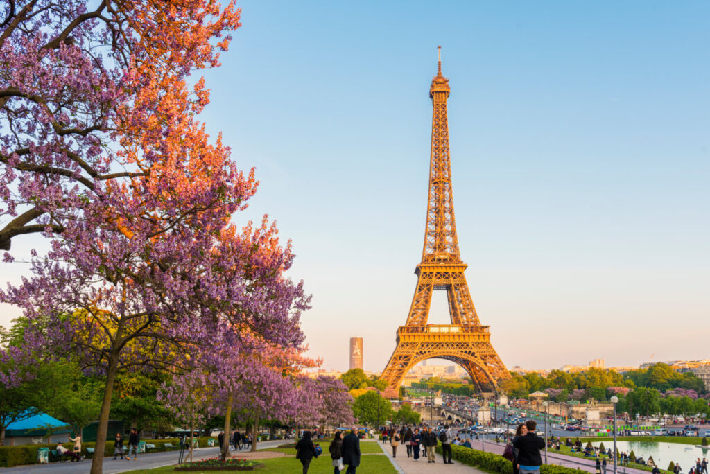 Eiffel Tower in Paris during spring at sunset, showcasing a vibrant sky and the iconic structure silhouetted against it.