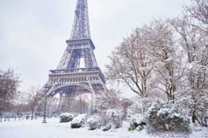 Snow-covered Eiffel Tower surrounded by a winter landscape, with heavy snowfall creating a serene, picturesque scene.