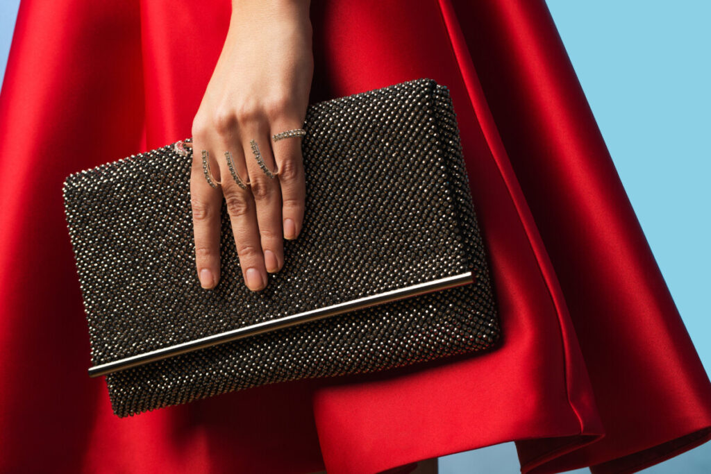 Woman in red dress holding black elegant clutch