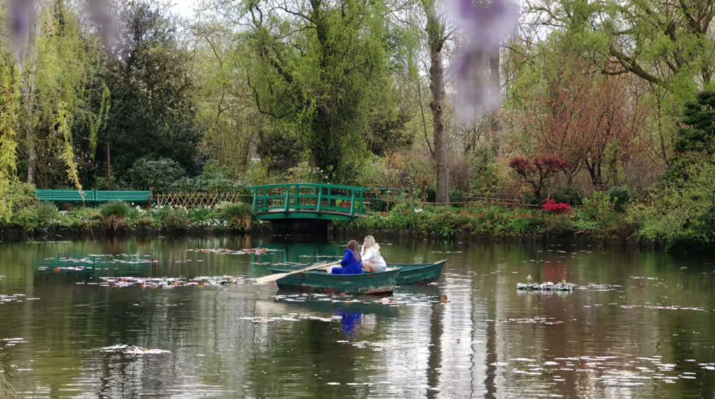 Camille Razat as Camille and Lily Collins as Emily talking at Monet's Garden in Giverny, as shown in Emily in Paris, season four, episode two
