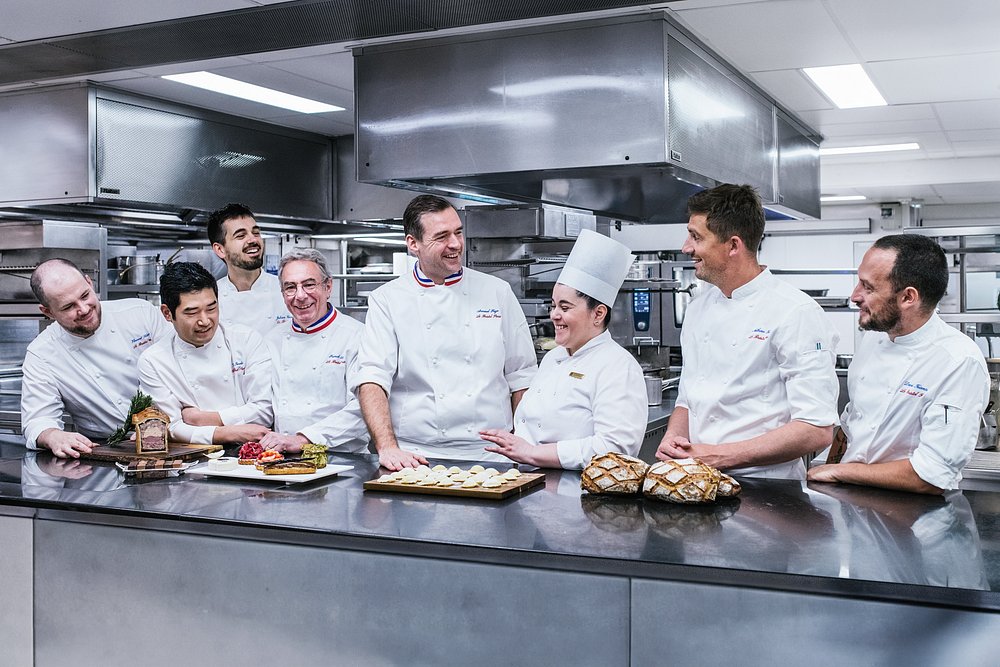 Group of Epicure staff and chefs posing together in a Paris restaurant kitchen