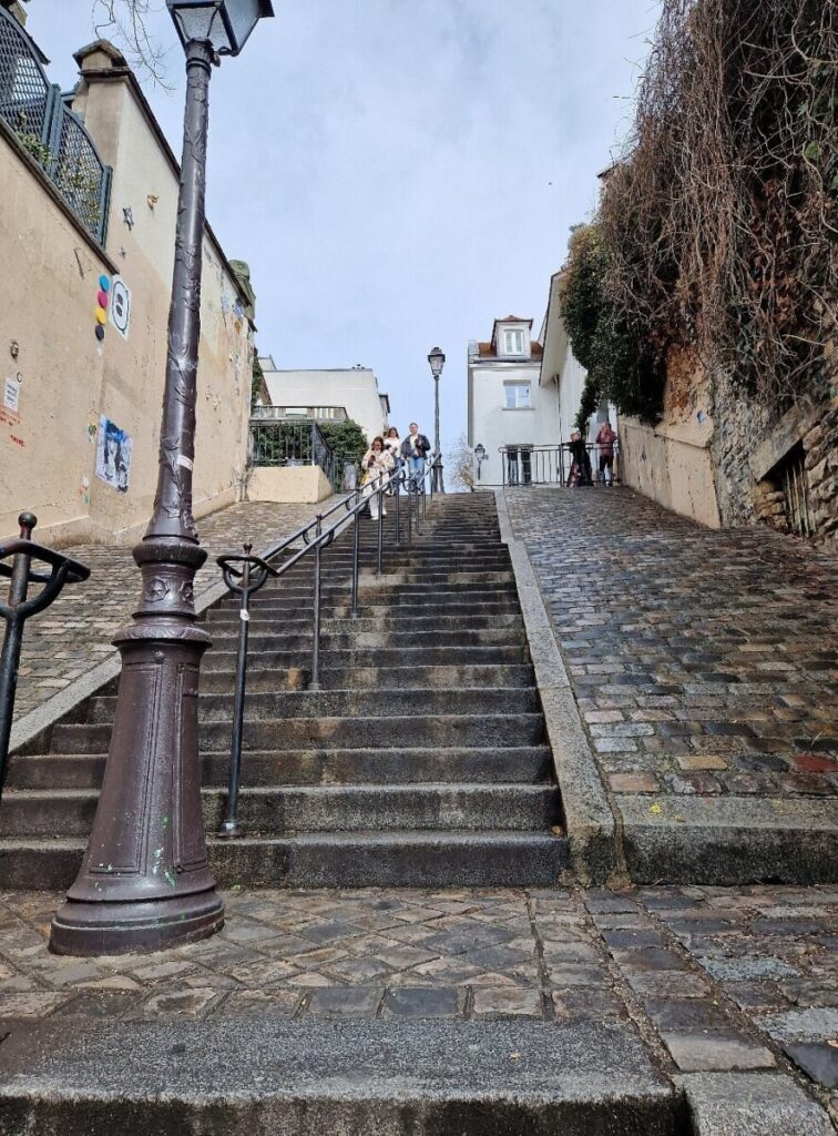 The steps of the Escaliers Du Calvaire feature a street lamp, casting light on the building's facade.