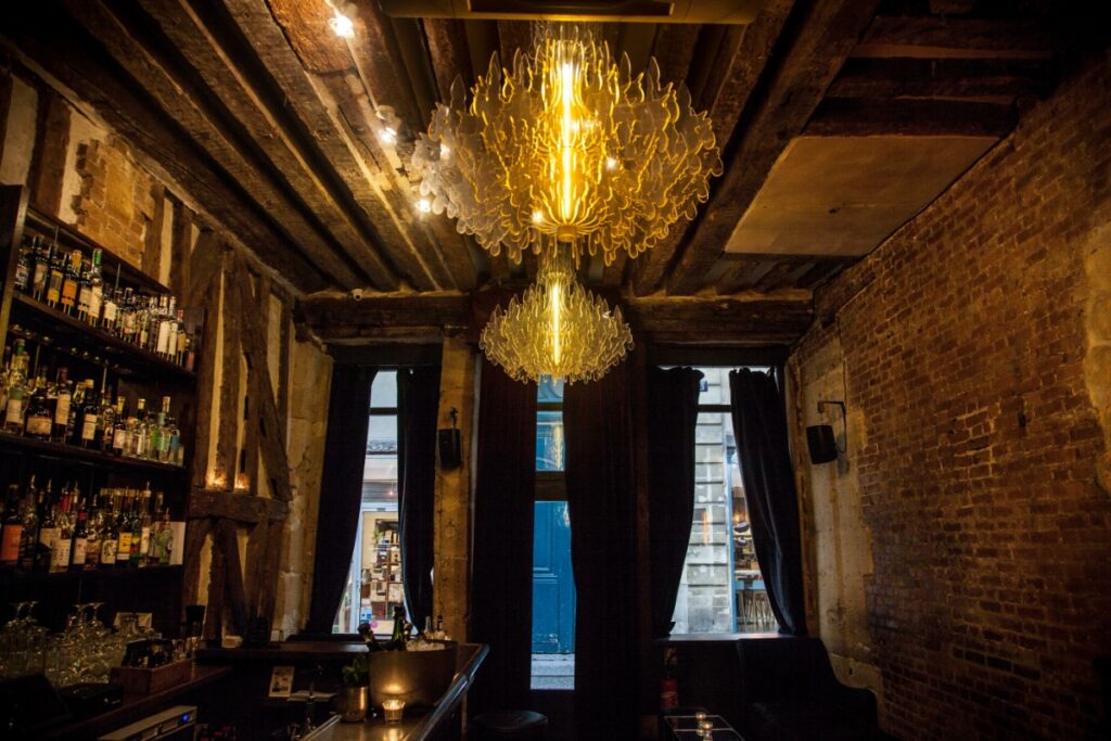 Interior of Experimental Cocktail Club in Paris, featuring a bar and an elegant chandelier hanging from the ceiling.