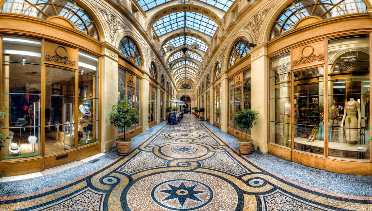 Interior view of Galerie Vivienne in Paris, showcasing elegant shops and a glass-roofed arcade filled with natural light.