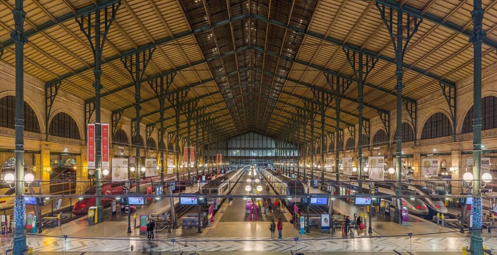 Interior of Gare Du Nord in Paris, bustling with people walking and waiting in the train station.
