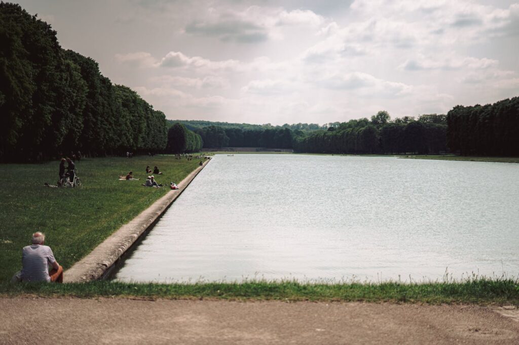 People realxing by the Grand Canal Versailles in Versailles, France