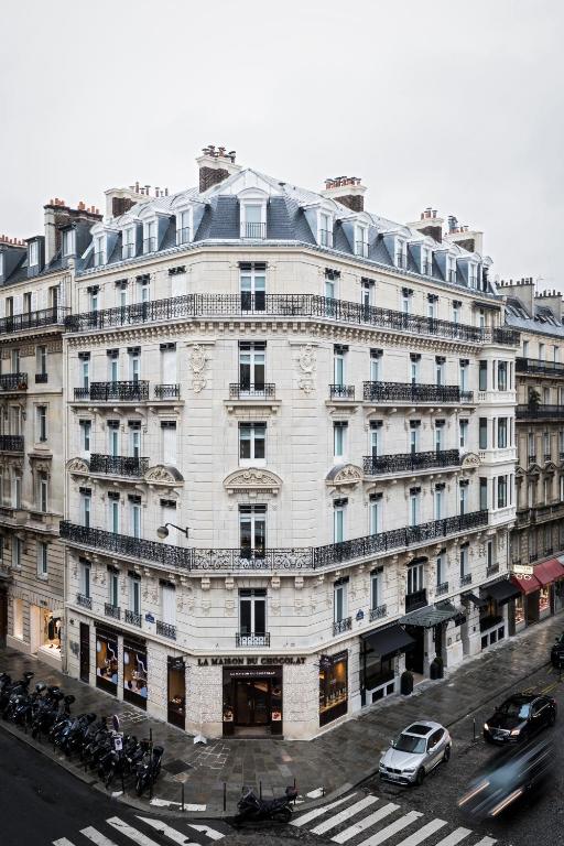 A classic Parisian building at a street corner with a patisserie on the ground floor and a clear view of its intricate facade and balconies.
