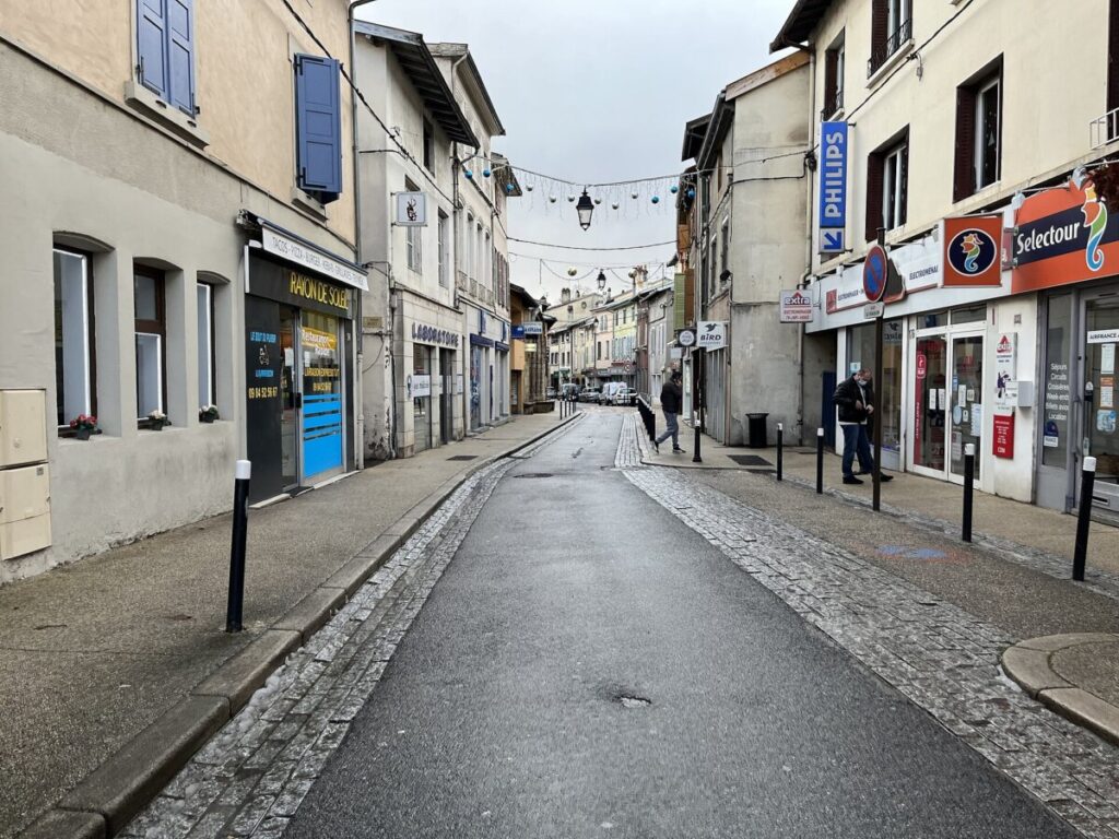 Person walks down Grande Rue in France, flanked by several buildings along the street.