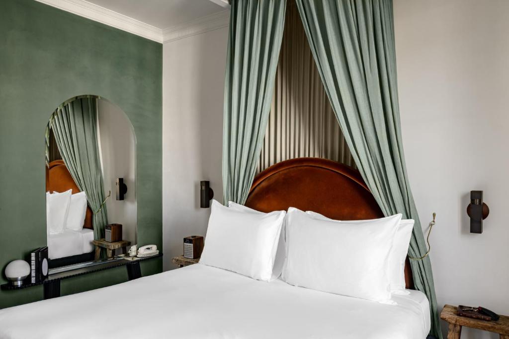 Cozy bed with white linens and pillows, set in a modern room at Grands Boulevards Experimental.