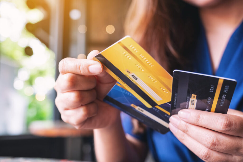 Closeup of a woman selecting a credit card from a group, focused on her hand and the cards.