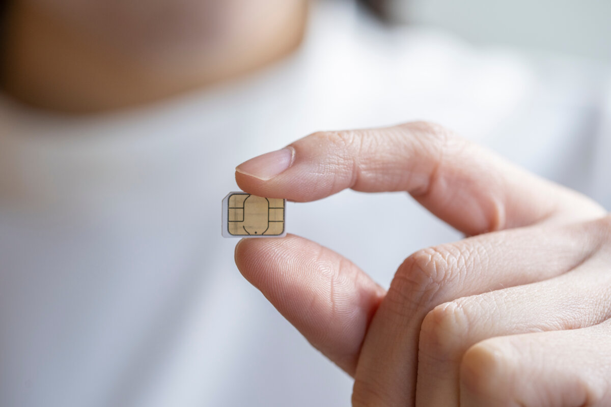 Close-up of a man holding a SIM card between his fingers, showcasing the card's design and details.