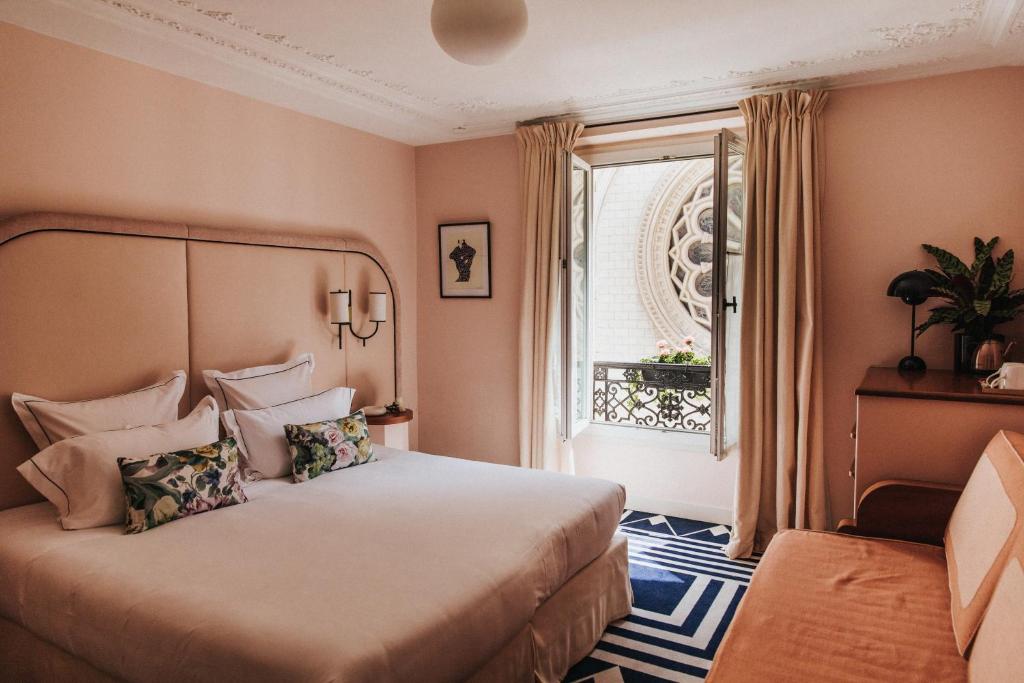 Elegant hotel room with stylish furnishings, soft bedding, and large windows overlooking a Parisian street at Hôtel Bienvenue.