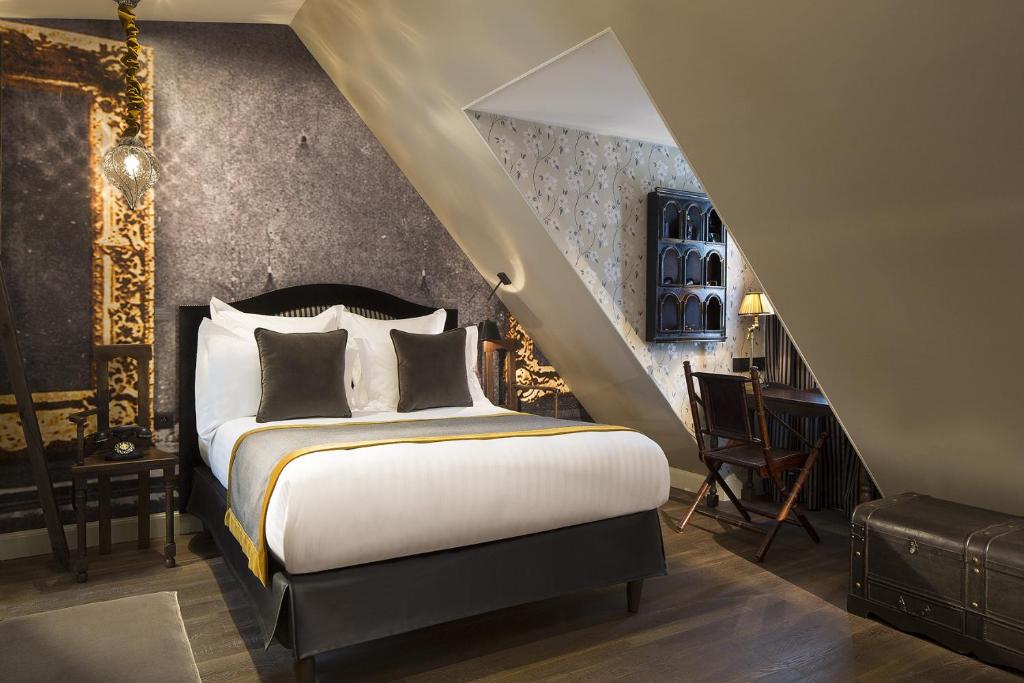 Elegant bedroom in Hôtel Da Vinci & Spa, Paris, showcasing a bed, a chair, and a stylish mirror.