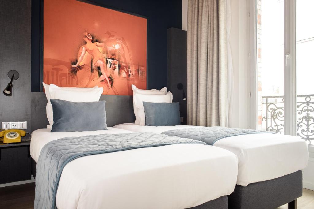 Hotel room at Hôtel des Arts Bastille featuring two beds and a decorative painting on the wall.