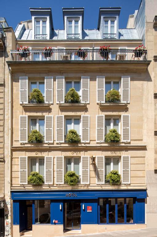 The exterior of Hôtel des Arts Montmartre features classic architecture with colorful window shutters and a charming entrance.