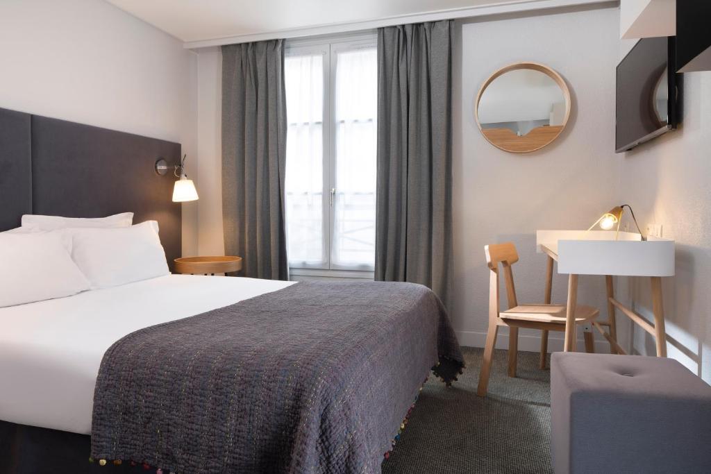 A cozy and tastefully decorated hotel room at Hotel d'Espagne, featuring modern furnishings, a comfortable bed with crisp linens, and large windows allowing natural light.