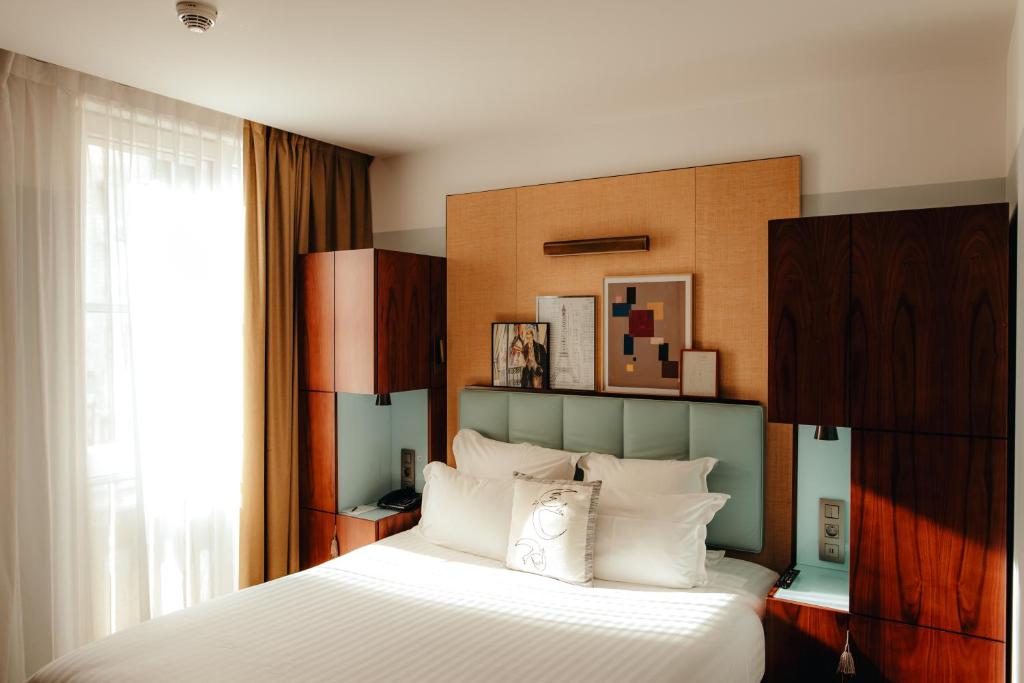 Interior of a hotel room at Hôtel Eiffel Blomet, Paris, showcasing a bed, a desk, and a window.