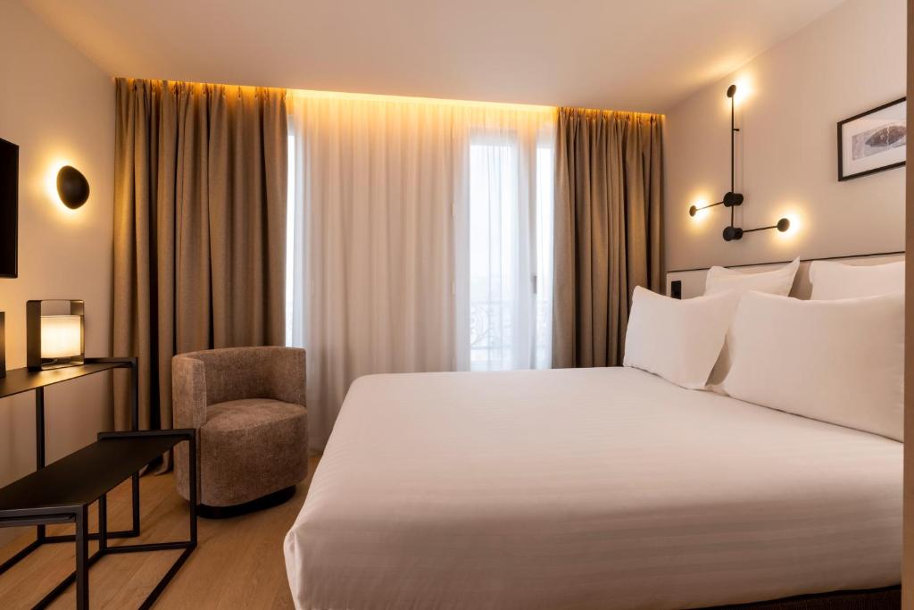A stylish and modern hotel room at Hôtel Esté Paris, featuring sleek furnishings, a cozy bed with crisp linens, and large windows allowing ample natural light.