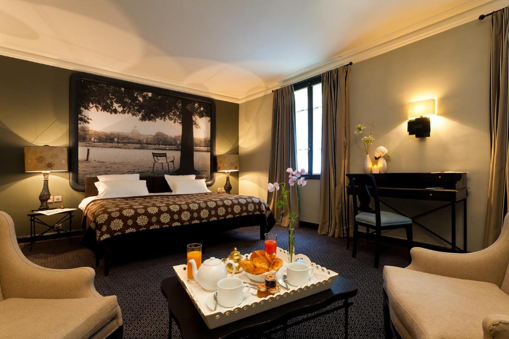 Interior of Hotel Fontaines du Luxembourg showing two beds and an artistic painting on the wall.