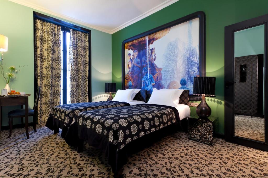 Hotel Fontaines du Luxembourg room featuring two beds and a decorative painting on the wall.