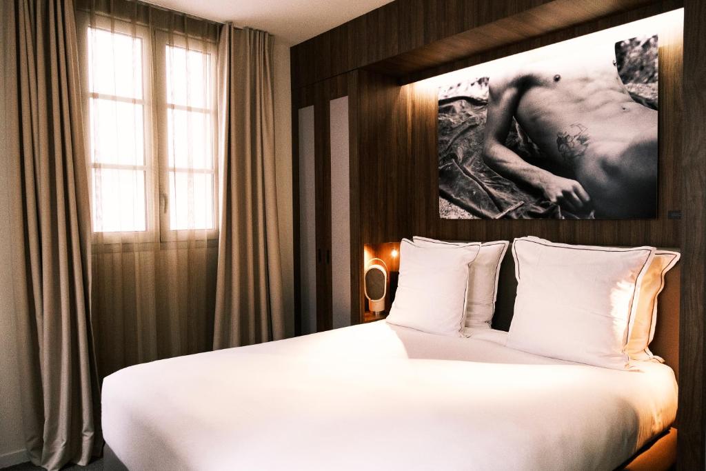 Interior of a Hôtel Jules & Jim room showcasing a bed and an art piece hanging on the wall.