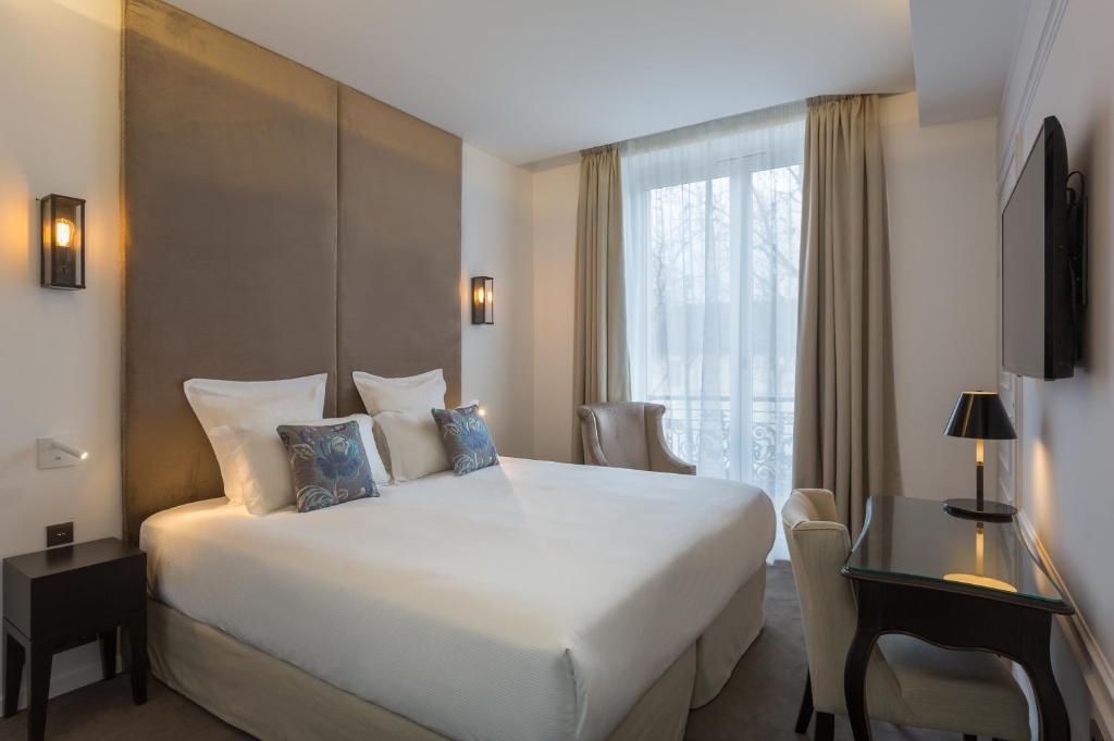 Interior of Hôtel La Comtesse in Paris, showcasing a spacious bed and a television in the hotel room.