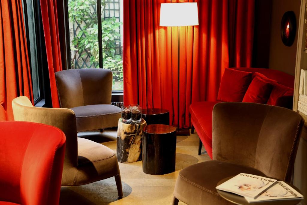 A cozy hotel lounge area with plush red and taupe chairs, vibrant red curtains, and soft lighting creating a welcoming atmosphere.