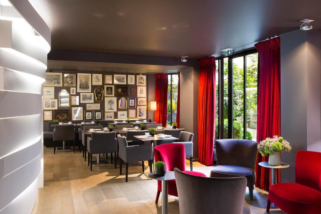 A stylish hotel dining area illuminated with soft lighting, featuring a variety of seating options and a wall of framed artistic displays.