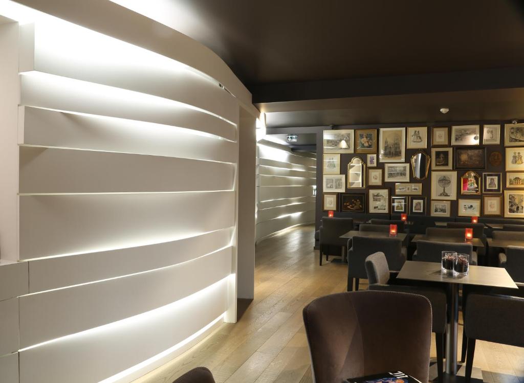 A modern and stylish restaurant interior with sleek wall lighting and a wall adorned with an eclectic collection of framed pictures.