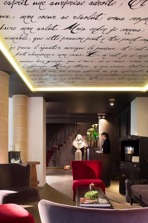 A sophisticated hotel reception area with scripted wall decor, elegant furniture, and a welcoming concierge desk.