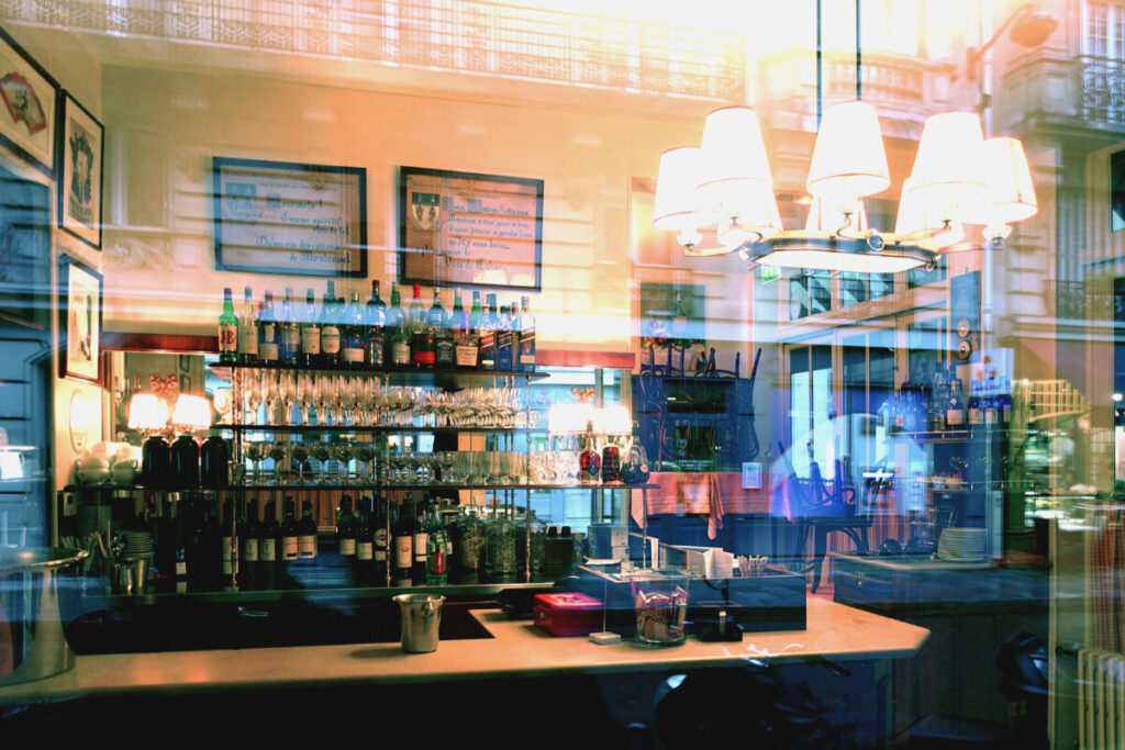 Cozy interior of a Parisian wine bar, featuring wooden shelves lined with wine bottles and intimate seating arrangements.