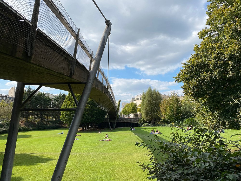 People relax on the grass beneath a bridge in Jardin de Reuilly Paul Pernin, Paris, France.