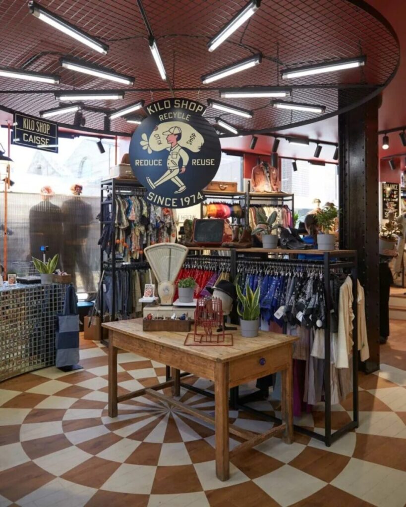 Inside Kilo Shop Paris Saint-Germain, featuring racks of stylish clothing and a lively atmosphere for shoppers.
