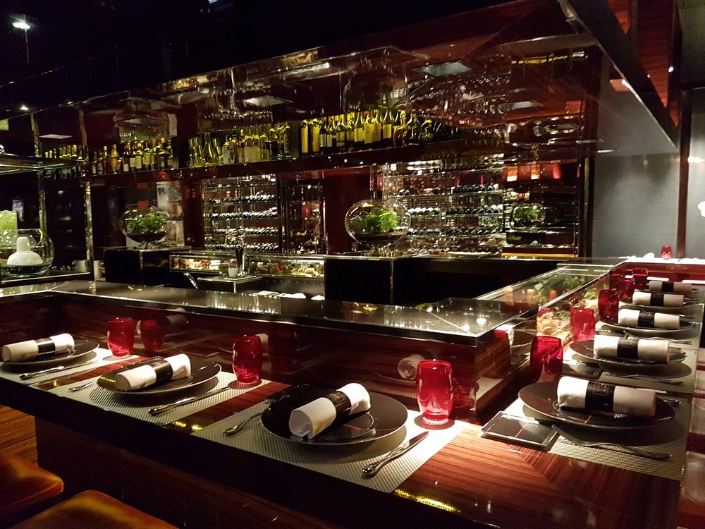 Interior of L'Atelier de Joël Robuchon featuring a long table surrounded by red chairs in Paris, France.