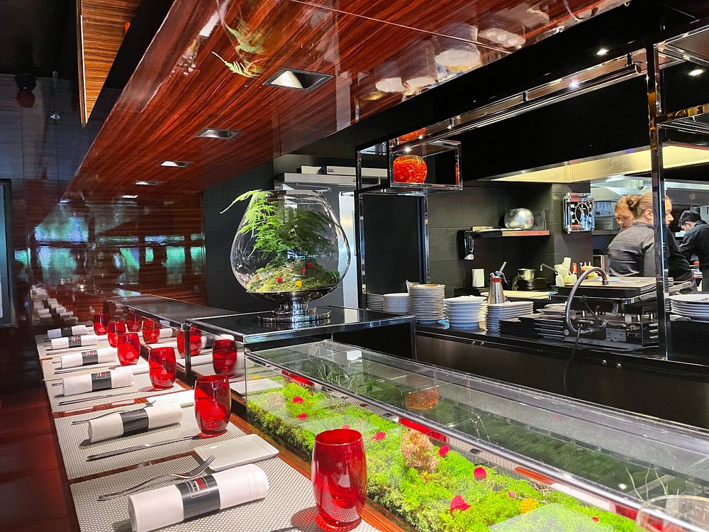 Interior of L’Atelier de Joël Robuchon in Paris, showcasing a bar with a counter and a chef crafting sushi.
