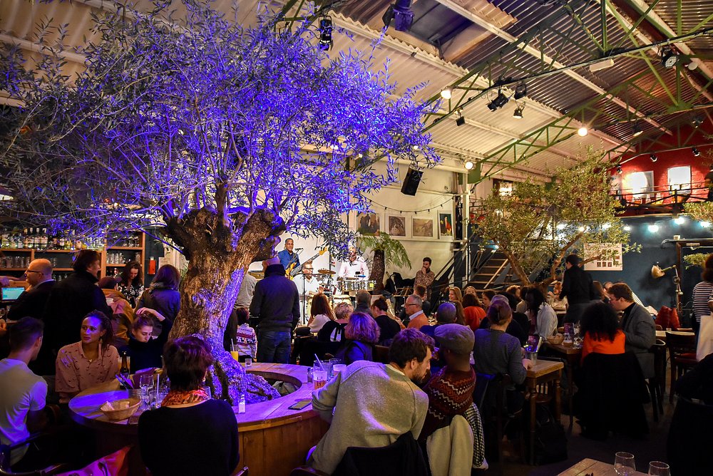 Lively scene of a large crowd dining at La Bellevilloise, a popular restaurant in Paris, France.