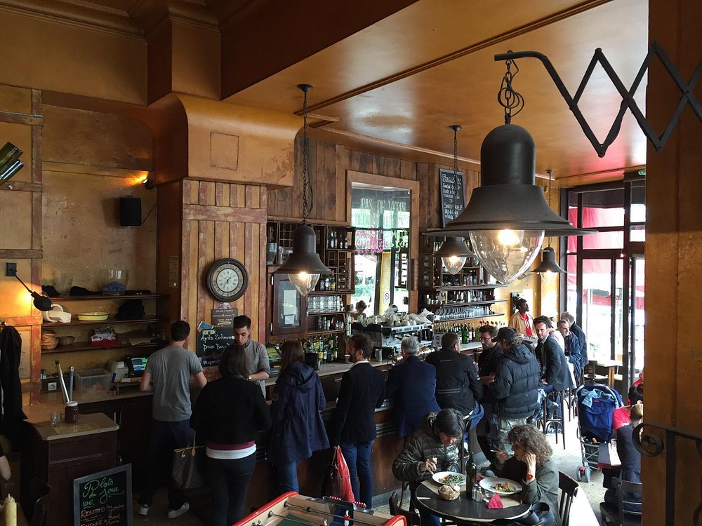 Patrons gathered at the bar in La Fourmi, a stylish interior in Paris, France, sharing drinks and lively discussions.