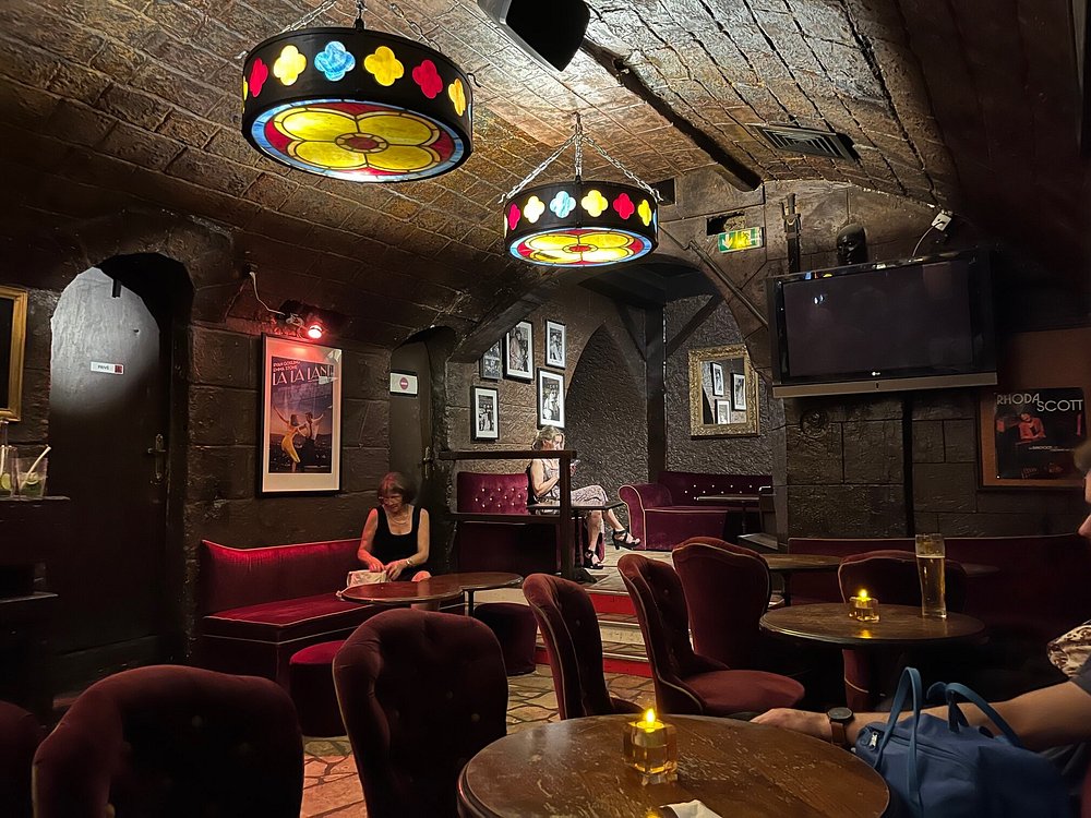 Woman at a table in the cozy, dim ambiance of Le Caveau de la Huchette bar in Paris.