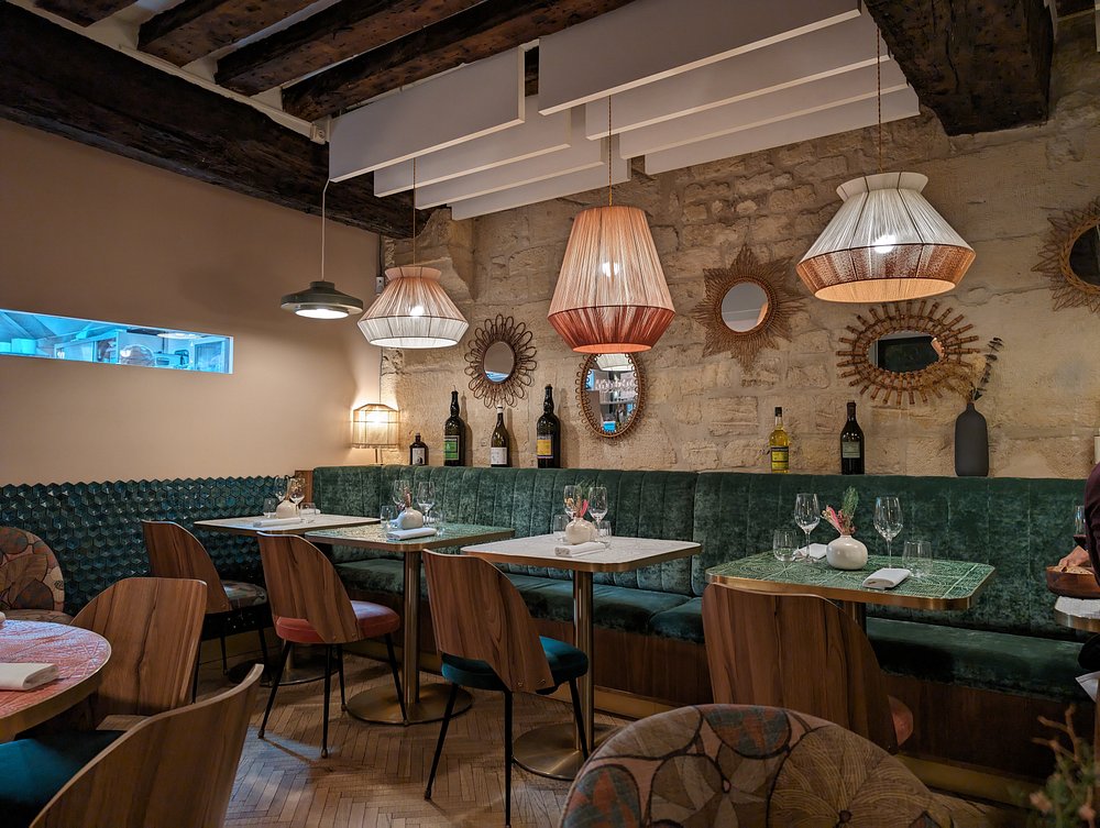 Interior of Le Christine in Paris, characterized by green walls and inviting wooden tables for dining.