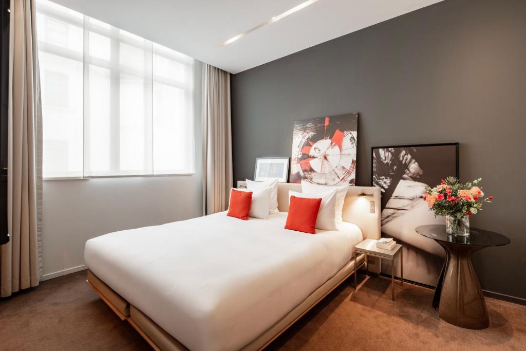 Elegant hotel room at Le Cinq Codet, Paris, showcasing a bed, a table, and an artistic painting above the furniture.