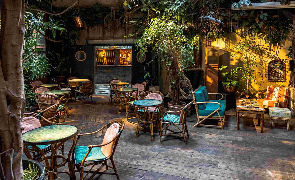 Interior view of Le Comptoir Général in Paris, showcasing wooden tables and chairs in a warm, inviting setting.