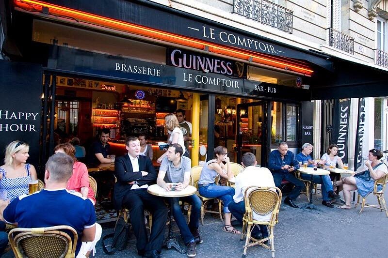 People dining at outdoor tables outside Le Comptoir Rugby Bar in Paris, France, enjoying the lively atmosphere.