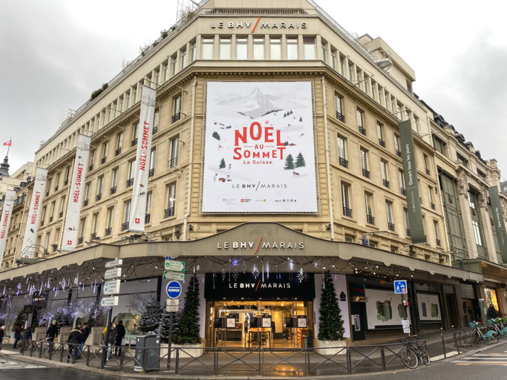 BHV Marais building with festive Christmas decorations and a large banner reading "Noël au Sommet."