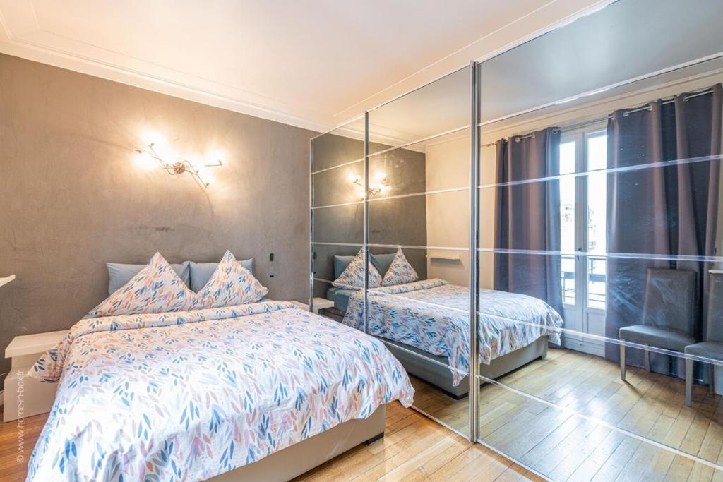 Cozy bedroom in Le Parisien Paris featuring a bed and a mirror, showcasing a stylish and inviting atmosphere.