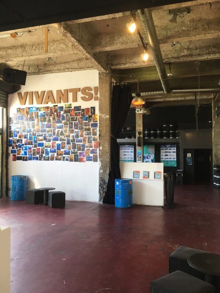 Interior view of Le Point Éphémère in Paris, showcasing a large sign displaying the word "vivants."