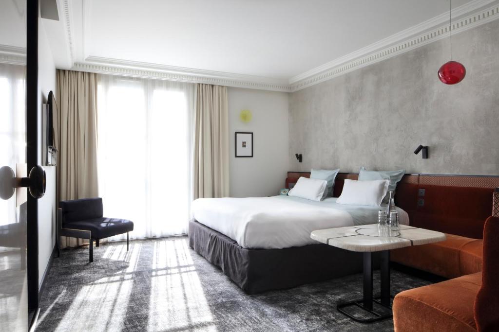 Interior of a hotel room at Les Bains Paris, with a neatly made bed, a chair, and a table, set in Paris, France.