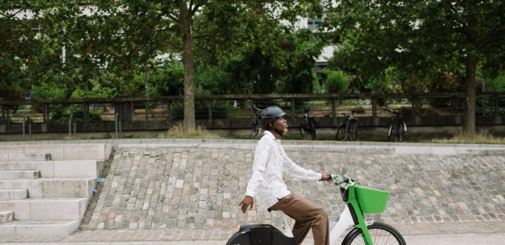 Individual cycling on a Lime Bike, surrounded by urban scenery and greenery, promoting eco-friendly transportation.