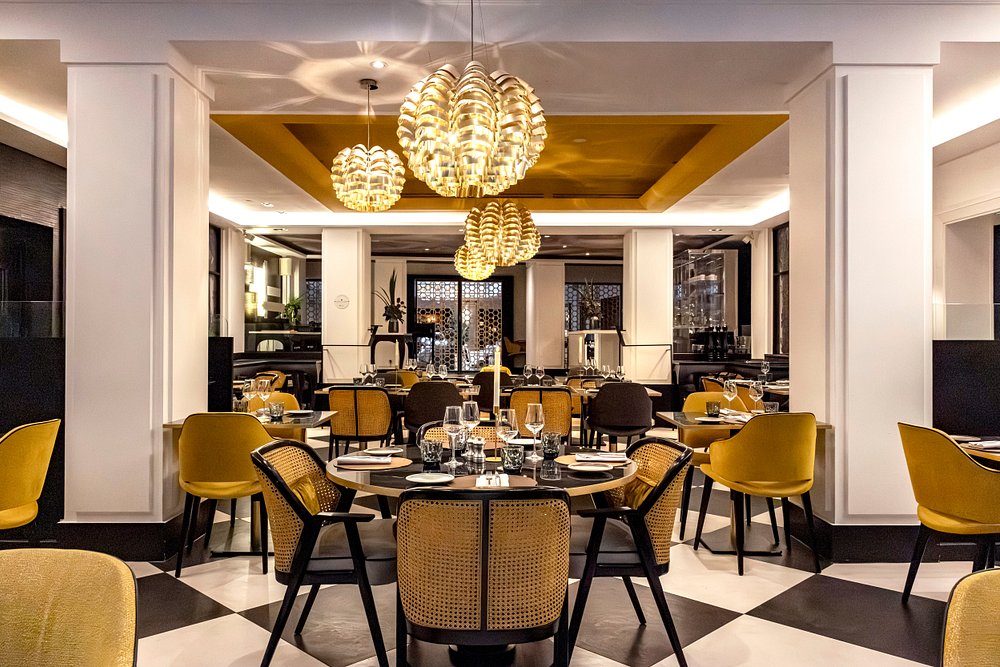 Interior of Maison Blossom Paris, showcasing yellow chairs and a classic black and white checkered floor design.