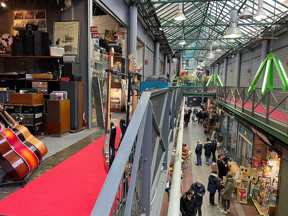 Inside Marché aux Puces de Saint-Ouen in Paris, a vibrant market showcasing numerous guitars and musical instruments.